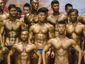 Bodybuilders flex muscles for judges on stage during the Hong Kong Bodybuilding Championship on June 29, 2014 at the Queen Elizabeth Stadium in Hong Kong, Hong Kong.