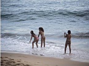 Brazilian women take pictures on a beach of Port Da Barra in Salvador on June 26, 2014, during the 2014 FIFA World Cup tournament.
