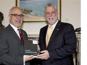 Quebec Premier Philippe Couillard, right, is handed a copy of the provincial budget by Finance Minister Carlos Leitao, Wednesday, June 4, 2014 at his office in Quebec City. The budget will be presented at the National Assembly later in the afternoon. THE CANADIAN PRESS/Jacques Boissinot