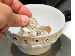 A customer drops a coin in a tip jar at a sandwich shop.