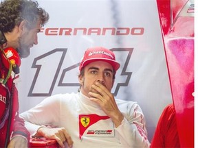 Ferrari F1 driver Fernando Alonso of Spain speaks with a technician in his team garage during the second free practice session for the Canadian Grand Prix at the Circuit Gilles Villeneuve in Montreal on Friday, June 6, 2014.