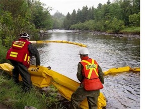 Fuel spill technicians install an oil absorbent boom in an inlet of the Chaudière River in Lac-Mégantic after the fatal train crash and explosion on July 6. Thousands of litres of crude oil were spilled in the river, causing concerns about damage to the environment.