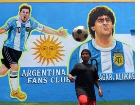 An Indian boy heads a football in front of graffiti of Argentine soccer player Lionel Messi at the roadside in Kolkata on June 10, 2014.