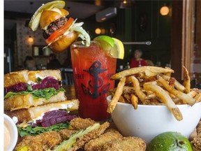 Left to right: the beet and arugula grilled cheese sandwich, a Bloody Caesar served with a speared mini-burger and regular fries with avocado fries in the foreground at L’Gros Luxe.