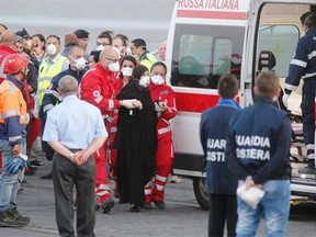 Members of the Italian Red Cross evacuate some of survivors of a migrant boat shipwreck after unloaded from an Italian warship at the Catania harbour on May 13, 2014 after being rescued, as Italy threatened to send asylum-seekers across Europe without more help to stem a wave of arrivals from North Africa. Hearses carrying the 17 coffins could be seen lined up in the port of Catania in Sicily as the Grecale frigate docked and dozens of medical personnel stood by to assist the survivors in four tents set up especially. “Our society is getting used to this tragic normality. AFP PHOTO / MARCELLO PATERNOSTROMARCELLO PATERNOSTRO/AFP/Getty Images ORG XMIT: —