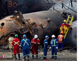 Cleanup crews take a break as they prepare to remove one of the toppled rail cars in Lac-Mégantic on Friday July 19, 2013. A Montreal, Maine and Atlantic Railway train became a runaway train and derailed, exploding in the centre of Lac-Mégantic on July 6th.