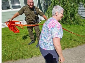 Irene Jacques, right, gets ready to cross a security barrier as a Surete du Quebec officer removes it, opening another zone for further 600 train crash evacuees to return home in Lac-Mégantic, Thursday  July 11, 2013.  Jacques hospitalized friend lives in the former security zone and had to be escorted by police daily to feed her friend’s cats.