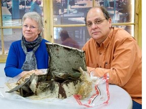 Diane Roy and Pierre Paquet look over the petty-cash box that was recovered from Lac-Mégantic’s only library, which was levled  in July after a runaway tanker train derailed and exploded. The dented metal box contained about $500 in rolls of coins and oily bills.