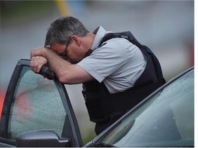 An RCMP officer rests his head at a roadblock in Moncton, N.B. on Thursday. Three RCMP officers were killed and two injured by a gunman on Wednesday.