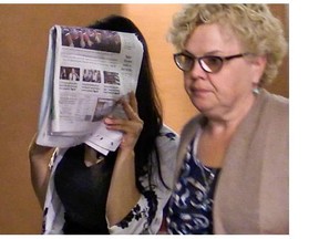 Emma Czornobaj hides her face from the media with a Gazette as she leaves the courtroom with her mother, Mary Hogan, at the Montreal courthouse on Friday, June 20, 2014 following her conviction.
