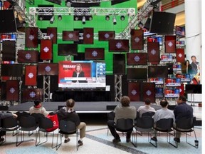 People watch the CBC broadcast of their own cutbacks from inside the main foyer of the CBC building in Toronto on Thursday, April 10, 2014.