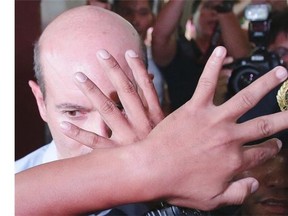 Philippine police try to cover the face of Italian diplomat Daniele Bosio as he is chased by reporters while entering the courtroom for his arraignment at the City Prosecutor's office at Binan township, Laguna province, south of Manila, Philippines, Wednesday, June 18, 2014.