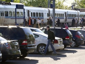 Passengers wait to board an AMT train near one of the parking lots at the Pierrefonds-Roxboro Train Station in Montreal, Tuesday, May 20, 2014.  The AMT just announced a pilot project that will see a monthly fee attached to a certain number of parking spots at select train stations.