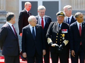 Russian President Vladimir Putin, top left, walks towards his position for a group photo as U.S. President Barack Obama, bottom right, Canadian Prime Minister Stephen Harper, top left, Ukrainian president-elect Petro Poroshenko, bottom left, and other leaders get ready, during a commemoration for the 70th anniversary of the D-Day landings, in Benouville, Normandy, France, Friday, June 6, 2014.