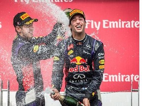 Red Bull F1 driver Daniel Ricciardo of Australia, right, celebrates his first place finish along with teammate Red Bull F1 driver Sebastian Vettel of Germany, left, who finished third, at the Canadian Grand Prix at the Circuit Gilles Villeneuve in Montreal on Sunday, June 8, 2014.