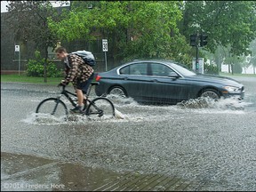 A cyclist churns through deep water after flash flooding from a severe storm turned streets into rivers and lakes in this view at boul St Joseph and Broadway St in Lachine Quebec, Tuesday, June 3, 2014. Photo ©2014 Frederic Hore, RemarkableImages.ca