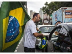 A street vendor sells flags to morning rush hour commuters in Sao Paulo on June 11, 2014. Brazil’s largest city and cars are decorated with murals and flags as they prepare to host the opening match of the FIFA 2014 World Cup between Brazil and Croatia on June 12th.
