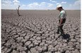 In this Aug. 3, 2011, photo, Texas State Park police officer Thomas Bigham walks across the cracked lake bed of O.C. Fisher Lake in San Angelo, Tex. Global warming is rapidly turning America the beautiful into America the stormy, sneezy and dangerous, according to a federal scientific report. Climate change’s assorted harms “are expected to become increasingly disruptive across the nation throughout this century and beyond,” the National Climate Assessment concluded. The report emphasizes how warming and its all-too-wild weather are changing daily lives, even using the phrase “climate disruption” as another way of saying global warming.
