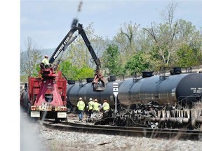 This file photo taken May 4, 2014 shows crews cleaning up the remains of the derailed CSX train along the James River in downtown Lynchburg, Va.  Montreal city councillors are calling on the Canadian government to force rail companies to divulge what hazardous materials are being transported through their territories so emergency crews can react quickly.