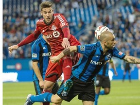 Toronto FC’s Alvaro Rey leaps onto Impact’s Marco Di Vaio during first-half action Wednesday, June 4, 2014, in Montreal.