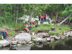 Workers remove soil as much as 2 metres from the shore along the Chaudière River in Lac-Mégantic Sunday, August 4, 2013. Water from the river remains safe to drink an expert panel has concluded.