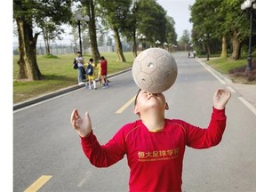 A young Chinese student balances the ball on his nose as he walks to a training match at the Evergrande International Football School on June 14, 2014 near Qingyuan in Guangdong Province, China. The 167-acre campus is the brainchild of property tycoon Xu Jiayin, whose ambition is to train a generation of young athletes to establish China as a football powerhouse.