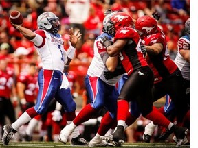 Alouettes quarterback Troy Smith throws the ball as Stampeders close in during first half CFL football action in Calgary, Saturday, June 28, 2014.