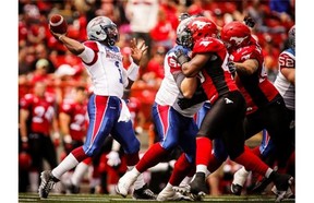 Alouettes quarterback Troy Smith throws the ball as Stampeders close in during first half CFL football action in Calgary, Saturday, June 28, 2014.
