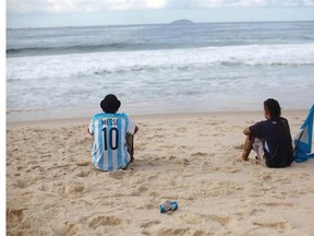Argentina soccer fans, one wearing a Lionel Messi soccer jersey, sit on Copacabana beach the morning after thier team was defeated by Germany at the World Cup final, in Rio de Janeiro, Brazil, Monday, July 14, 2014.
