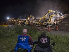 A couple watch as  demolition crew tears into the St-Charles overpass in Vaudreuil -Dorion on Saturday, July 19.