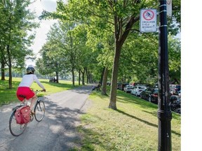 A cyclist rides past a sign banning cycling in Jeanne-Mance Park on Friday. The City has rescinded the ban and ordered the sign to come down.