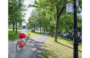 A cyclist rides past a sign banning cycling in Jeanne-Mance Park on Friday. The City has rescinded the ban and ordered the sign to come down.