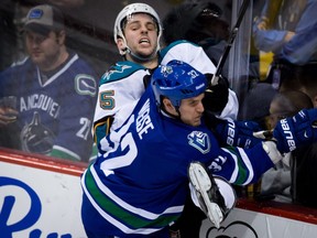 Vancouver Canucks' Dale Weise, right, checks San Jose Sharks' Jason Demers during a game in Vancouver on March 5, 2013.