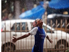 An Indian Muslim boy stretches his arms and looks skyward as rain falls in Hyderabad, India, Tuesday, July 1, 2014.