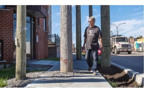 A local resident weaves his way through new and old hydro poles along a new sidewalk at the corner of Henri-Bourassa Blvd. and Hébert Ave.