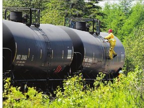 Transport Safety Board inspectors examine one of fuel tankers involved in the Lac-Mégantic disaster a year ago.