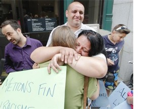 Renata Buzas (facing camera) hugs a supporter outside the Immigration Canada offices in Montreal Wednesday, July 2, 2014, after they found out they would be getting a stay of deportation to Hungary. Behind, on the left is the Buzas family lawyer Éric Taillefer, left, Tibor Buzas and his and Renata’s son Tibor. The family, five people of Roma ethnic origin, were scheduled to be deported on Thursday. They and supporters held a rally to demand they be given permanent residence and not be returned to Hungary where racist violence against Roma is on the rise. They have been in Quebec since 2011. Other family members, from the left are: Mercedesz, Lilli and father Tibor. Man with sunglasses atop his head is close family friend Michael Crevier.