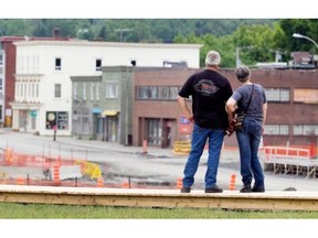 Standing on a new boardwalk, visitors look out at the former downtown core of Lac-Mégantic on Saturday. June 28.