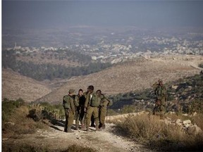 Israeli soldiers patrol near the area where the bodies of three Israeli teenagers were found, in the village of Halhul, near the West Bank city of Hebron, Tuesday, July 1, 2014.