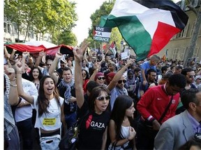 Pro-Palestinian demonstrators hold banners and shout slogans, in Paris, France, Wednesday, July 23, 2014 during a demonstration to protest against the Israeli army's shelling in the Gaza strip. Protesters marched through Paris against the Israel-Gaza war, under the watch of hundreds of police in an authorized demonstration days after two banned protests degenerated into urban violence.