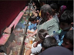 In this Monday, July 14, 2014 photo, displaced Palestinians fill empty bottles of water at the New Gaza Boys United Nations School, where dozens of families have sought refuge after fleeing their home in fear of Israeli airstrikes.