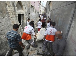 Palestinian medics carry a dead body found under the rubble of a home destroyed by an Israeli strike in the Shijaiyah neighbourhood of Gaza City, northern Gaza Strip, Sunday, July 20, 2014. Hundreds of panicked residents have fled the neighbourhood which they say has come under heavy tank fire from Israeli forces. Some reported seeing dead and wounded in the streets, with ambulances unable to reach the area. Israel widened its ground offensive early Sunday, sending more troops into the Hamas-ruled territory to destroy tunnels used by the Islamic militants to try to sneak into Israel.