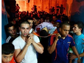 Palestinians carry the body of Yosuf abu Zaghah, 20, who was killed by the Israeli troops in the West Bank refugee camp of Jenin Early on Tuesday, July 1, 2014. Abu Zaghah, a Palestinian from the militant group Hamas was shot dead when he threw a grenade at forces carrying out an arrest raid in the West Bank hours after the discovery of the bodies of three Israeli teenagers who were abducted over two weeks ago, Israel’s military said Tuesday.
