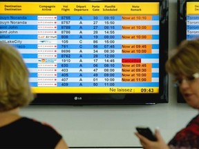 Passengers read the flight display at Pierre Elliott Trudeau International Airport in Montreal, Tuesday, July 23, 2014.