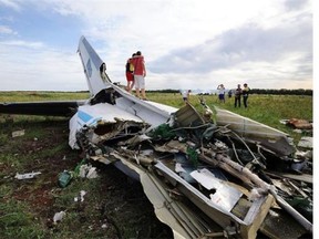 . People pose on July 14, 2014 while standing on the wreckage of a Ukrainian AN-26 military transport plane after it was shot down by a missile in the village of Davydo-Mykilske, east of Lougansk near the Russian border. Residents say that at least some of the crew were able to parachute from the plane before it crashed, but they did not know where they landed.