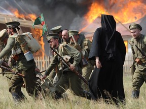 Actors dressed as Russian soldiers  and one dressed as priest take part in the re-enactment of the 1914 Battle of Tannenberg in Szkotowo, Poland, on Sunday, July 27, 2014, marking the 100th anniversary of the beginning of World War I. History enthusiasts from across Europe gathered to reconstruct the Battle of Tannenberg, an engagement between the Russian and German Empires in the first days of World War I.  (AP Photo/Alik Keplicz)