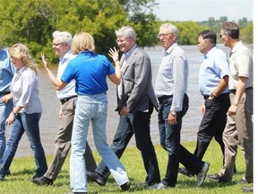 Prime Minister Stephen Harper talks with Brandon Mayor Shari Decter Hirst and other politicians while touring the Assiniboine River flooding in Brandon, Manitoba on Sunday, July 6, 2014.