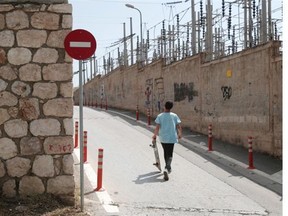 A skateboarder strolls near an electric station of Public Power Corporation (PPC) in Athens, on Wednesday, July 2, 2014. PPC workers began rolling strikes to protest against government plans to sell a stake in the company to private investors.