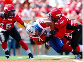 Stampeders’ Keon Raymond, left, and Charleston Hughes corral Alouettes running-back Brandon Whitaker during game at McMahon Stadium last week.