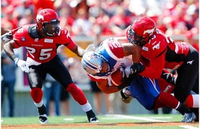 Stampeders’ Keon Raymond, left, and Charleston Hughes corral Alouettes running-back Brandon Whitaker during game at McMahon Stadium last week.